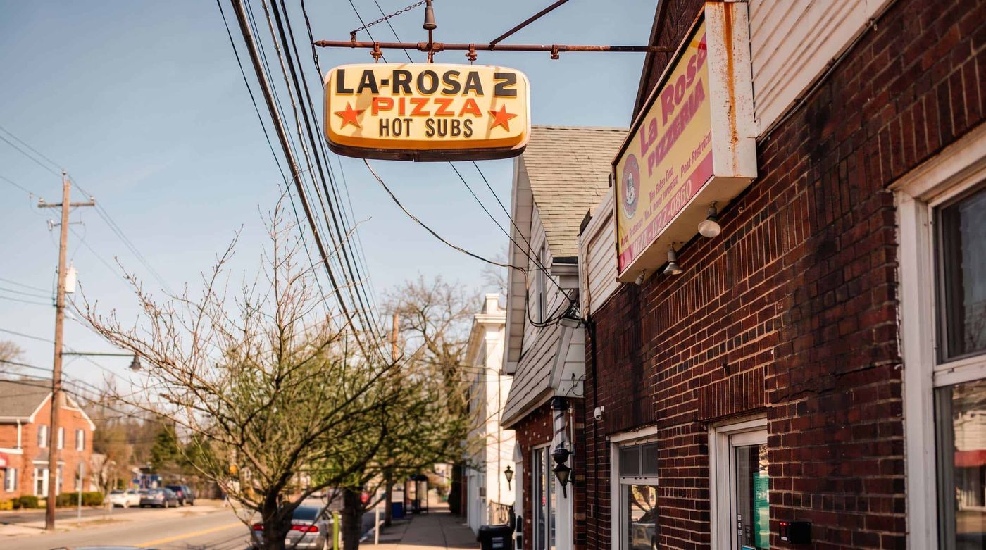 The La Rosa Pizza hanging sign above the sidewalk on Woodbridge Avenue